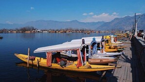 A row of yellow boats docked at a pier with mountains in the background. - Golden Crest Houseboats (Srinagar)