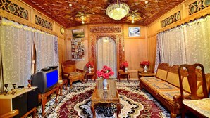 A traditional room with ornate wooden furniture, a chandelier, and a television. - Golden Crest Houseboats (Srinagar)