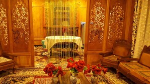 A traditional room with ornate wooden doors, a round table with a white tablecloth, and two chairs. - Golden Crest Houseboats (Srinagar)