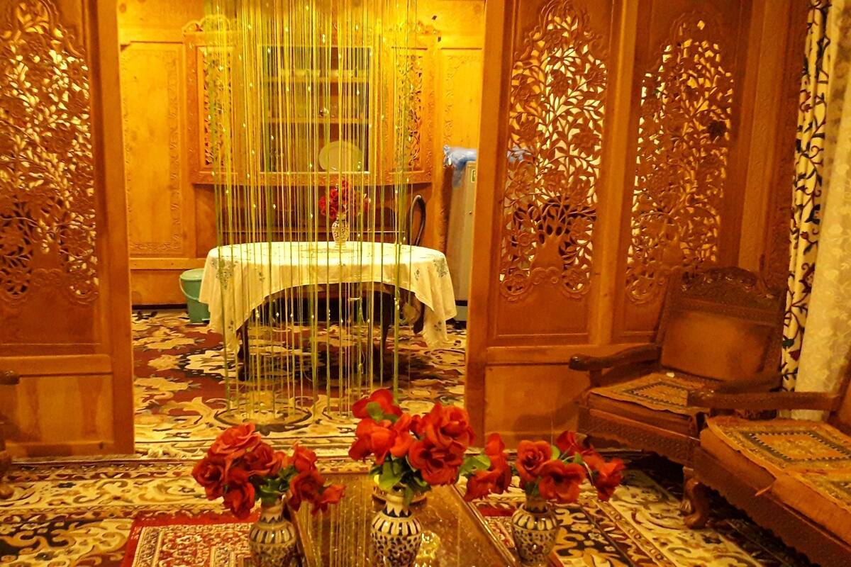 A traditional room with ornate wooden doors, a round table with a white tablecloth, and two chairs.