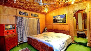 A traditional wooden room with a bed, a radio, and a painting on the wall. - Golden Crest Houseboats (Srinagar)