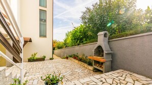 A patio with a stone floor, a stone fireplace, and potted plants. - Comfortable apartment PUH (Pula)