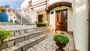 A hotel entrance with stone steps, a wooden door, and potted plants. - Comfortable apartment PUH (Pula)