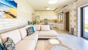 Un salon moderne avec un canapé beige, une table basse et un tableau représentant une scène de plage.