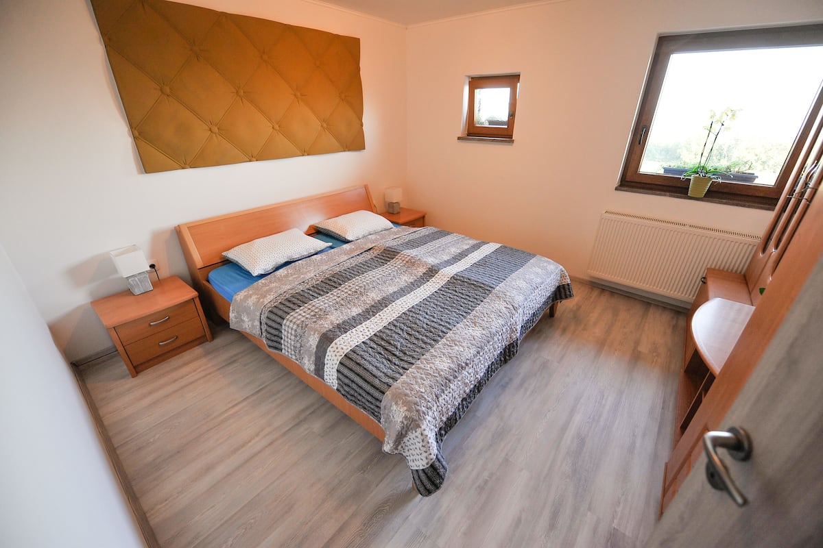 Ein Schlafzimmer mit einem Bett, einem Nachttisch, einem Fenster mit Blick und einer Heizung.