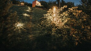 A house on a hill with a lit pathway leading to it. - Panorama Glamping Visole (Slovenska Bistrica)
