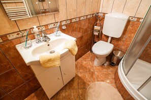 Et badeværelse med håndvask, toilet og bruser.