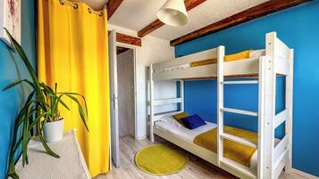A bunk bed room with a yellow curtain, a potted plant, and a blue wall.