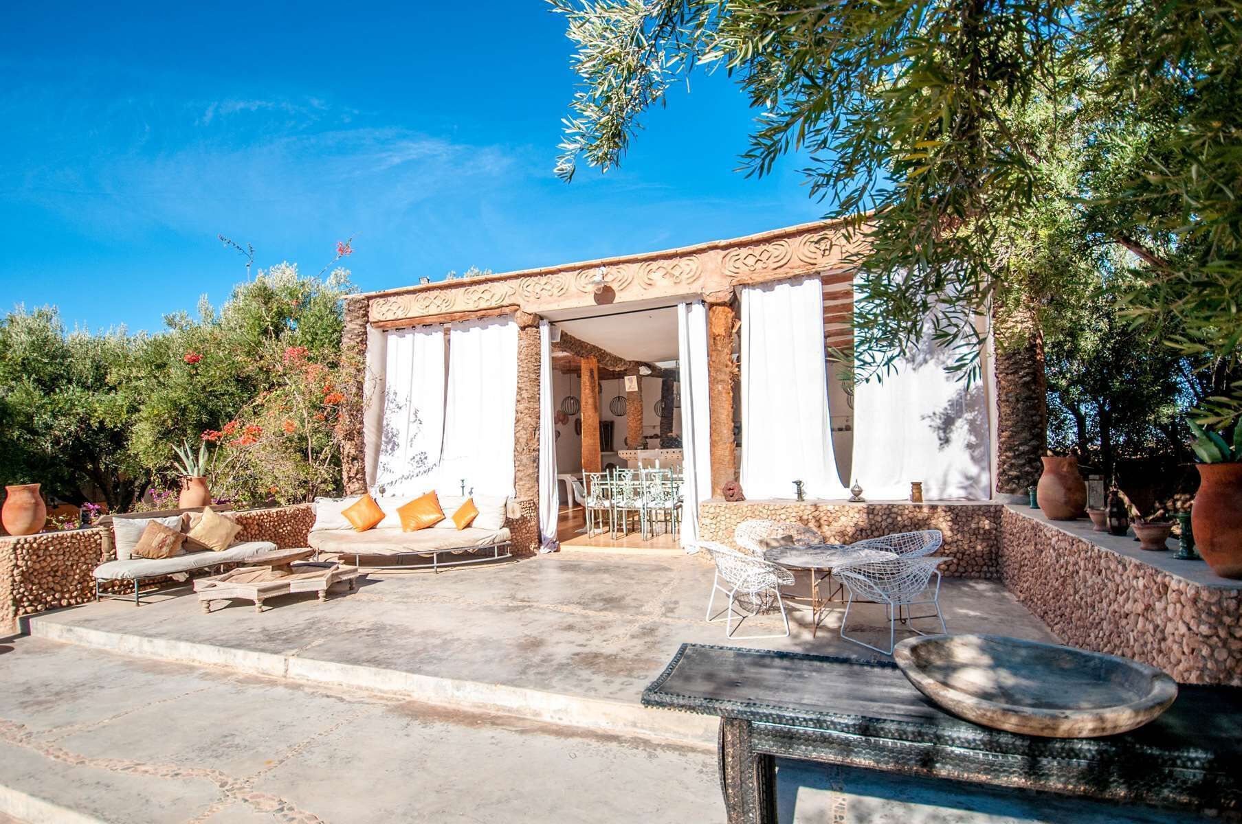 An outdoor seating area with a stone wall, a table with chairs, and a decorative bowl.