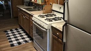 A kitchen with wooden cabinets, a gas stove, a microwave, and a refrigerator.