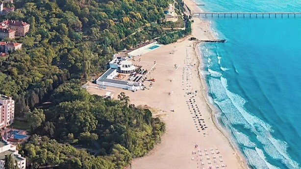 An aerial view of a coastal area with a beach, a pier, and a building complex with multiple structures. - Room-tia Maria is Situated in the Southe (Nessebar)