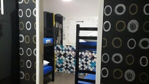 A room with a bunk bed, a desk, and a chair. There is a mirror on the wall and a ceiling fan. - O Hostel GRU-SP (Guarulhos)