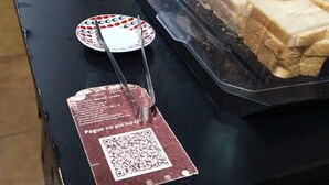 A buffet setup with a variety of food items, including sandwiches and condiments, displayed on a table with a QR code for ordering. - O Hostel GRU-SP (Guarulhos)