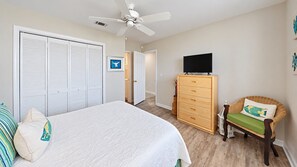 A bedroom with a bed, a wardrobe, a dresser, a chair, and a ceiling fan.