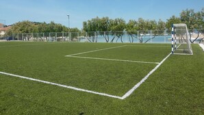 A soccer field with goalposts, surrounded by a fence and trees.