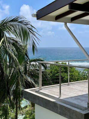 Un balcon avec vue sur l’océan et les palmiers.