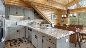 A kitchen with granite countertops, white cabinets, and a dining area with a table and chairs. - Abode at Black Bear #403, hot tub, pool & gym, steps to trails (Park City)