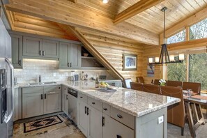 A kitchen with granite countertops, white cabinets, and a dining area with a table and chairs.