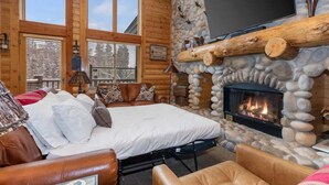 A log cabin interior with a bed, fireplace, and large windows. - Abode at Black Bear #403, hot tub, pool & gym, steps to trails (Park City)