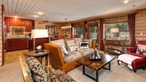 A cozy cabin interior with a wooden ceiling, a fireplace, a sofa, a red armchair, and a dining table. - Abode at Black Bear #103, hot tub, pool & gym, Deer Valley (Park City)