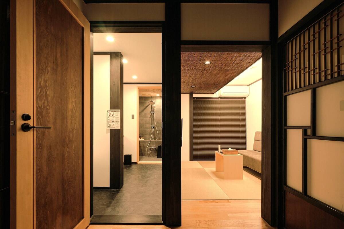 Een traditioneel Japans interieur met een houten deur, een tatami vloerkleed, een verschuifbare shoji scherm en een moderne douchecel.