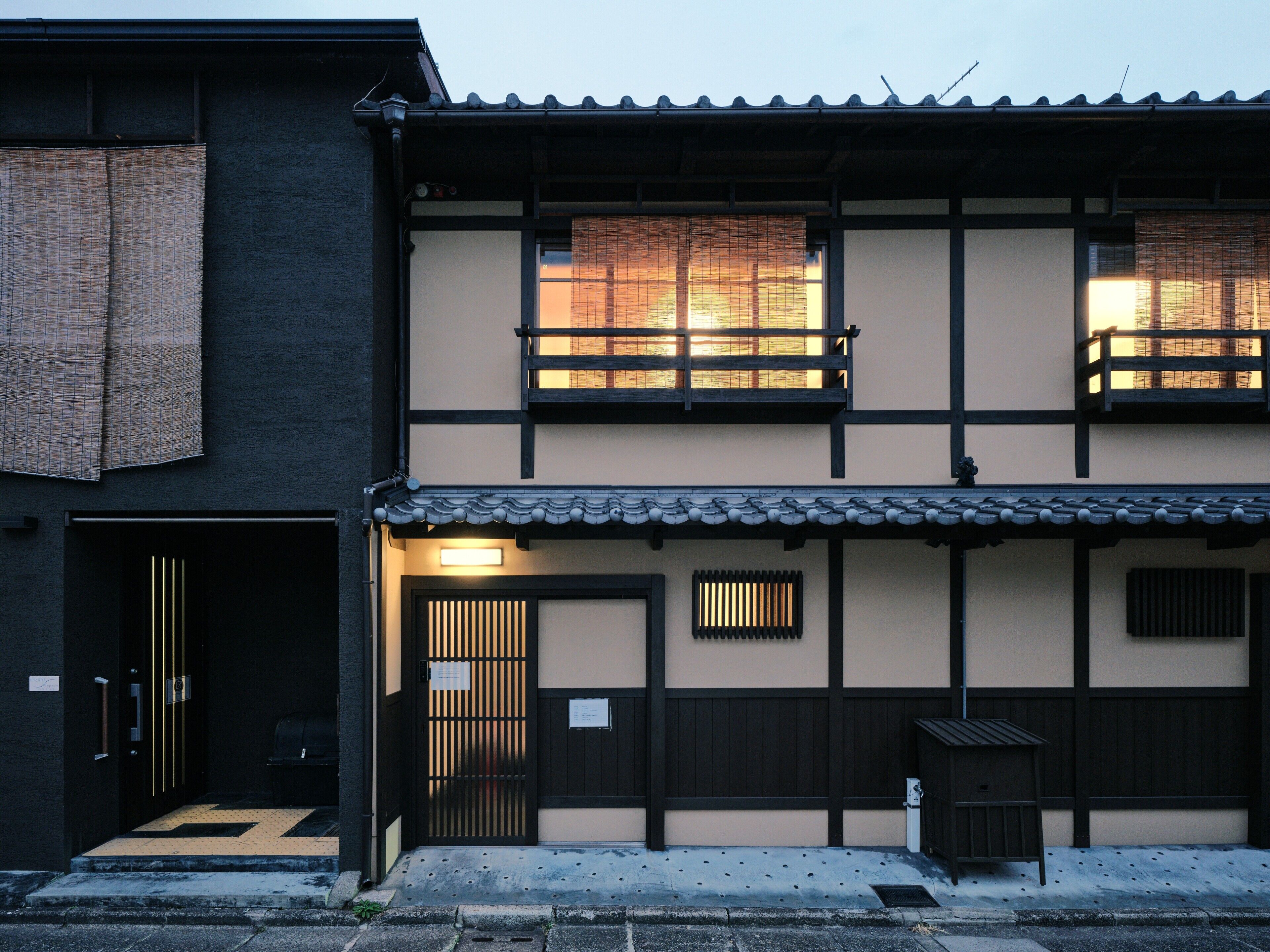 A traditional Japanese building with a dark exterior, a tiled roof, and a wooden gate.