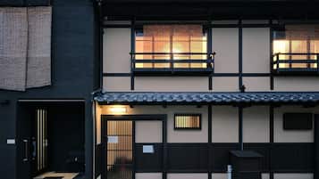 A traditional Japanese building with a dark exterior, a tiled roof, and a wooden gate.