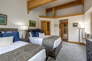 Experience a spacious and inviting room with two beds, a bedside table, and a dresser, perfect for a comfortable stay.