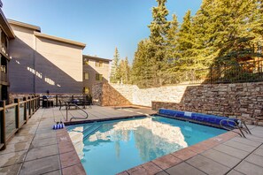 Guests can enjoy a pool surrounded by a stone wall and metal fence.