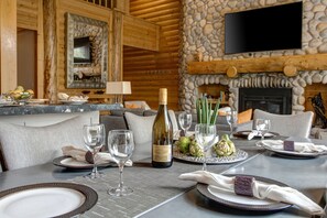 Enjoy a formal meal in this cozy cabin-style dining area with a stone fireplace and comfortable seating.