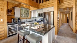 A log cabin-style kitchen with a central island, stainless steel appliances, and wooden walls. - Abode at Black Bear #431, hot tub, pool, free Main Streetreet shuttle (Park City)