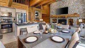 A modern kitchen with stainless steel appliances, a stone fireplace, and a dining area set for four. - Abode at Black Bear #431, hot tub, pool, free Main Streetreet shuttle (Park City)