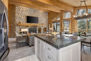 A kitchen with a stone wall, wooden ceiling, and a large island with a marble countertop.