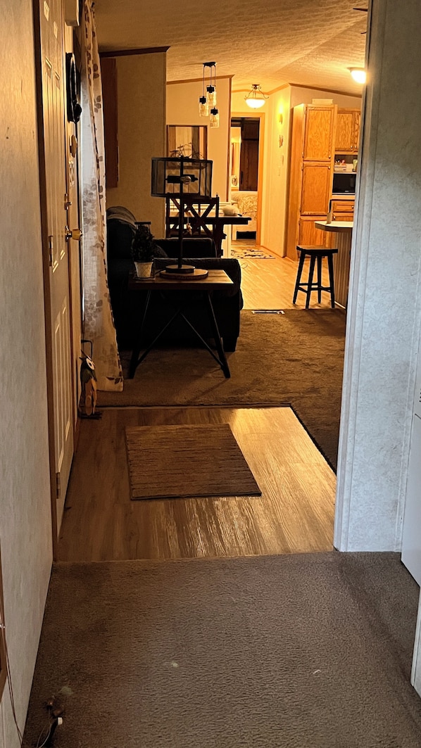 A hallway leading to a living room with a sofa, a coffee table, and a rug. There is a staircase leading to another level. - AN OWL and the MOON.  Get-Away in Mohican State Park. Location perfect! (Loudonville)
