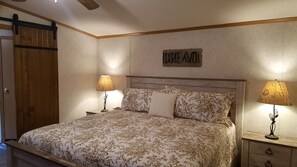 A bedroom with a bed, two nightstands, a wooden wardrobe, and a sign on the wall. - AN OWL and the MOON.  Get-Away in Mohican State Park. Location perfect! (Loudonville)