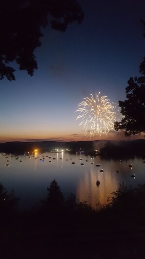 A nighttime view of a lake with fireworks in the sky, boats on the water, and trees framing the scene. - AN OWL and the MOON.  Get-Away in Mohican State Park. Location perfect! (Loudonville)