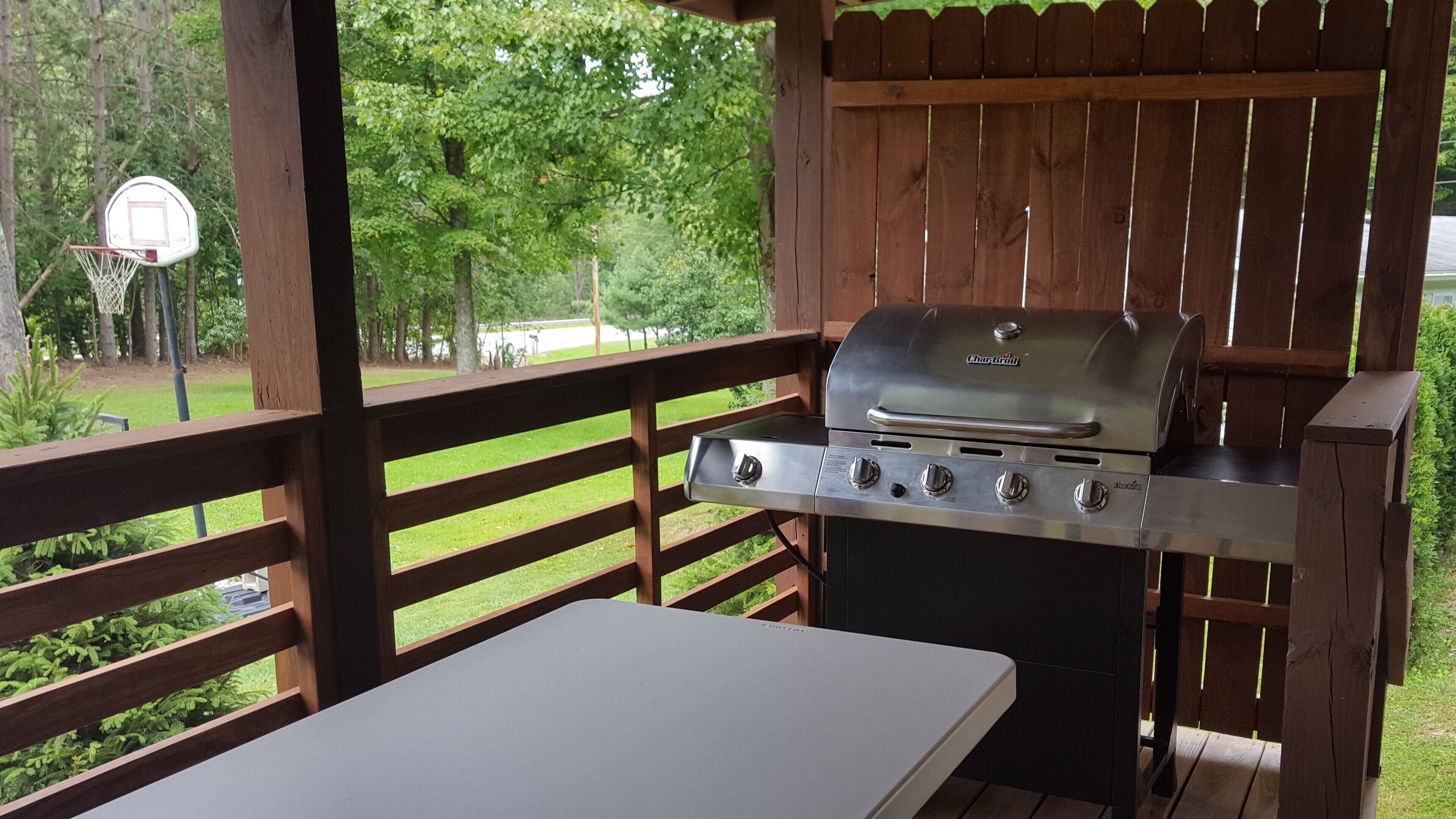 A covered outdoor barbecue area with a grill and a table.