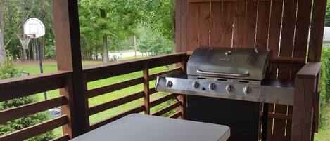 A covered outdoor barbecue area with a grill and a table.