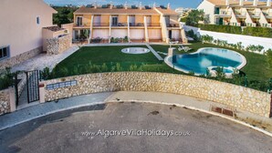 A villa with a swimming pool, a stone wall, and a well-maintained lawn.