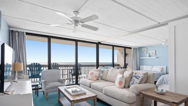 Een ruim balkon met uitzicht op de oceaan, voorzien van een bank, stoelen en een eettafel.