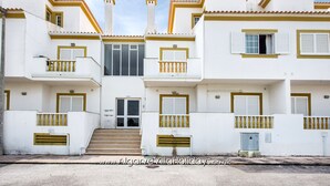 A white building with yellow trim, multiple balconies, and a central entrance with steps. - Apartment AG - O Monte 3 bedroom apt with large pool (Albufeira)