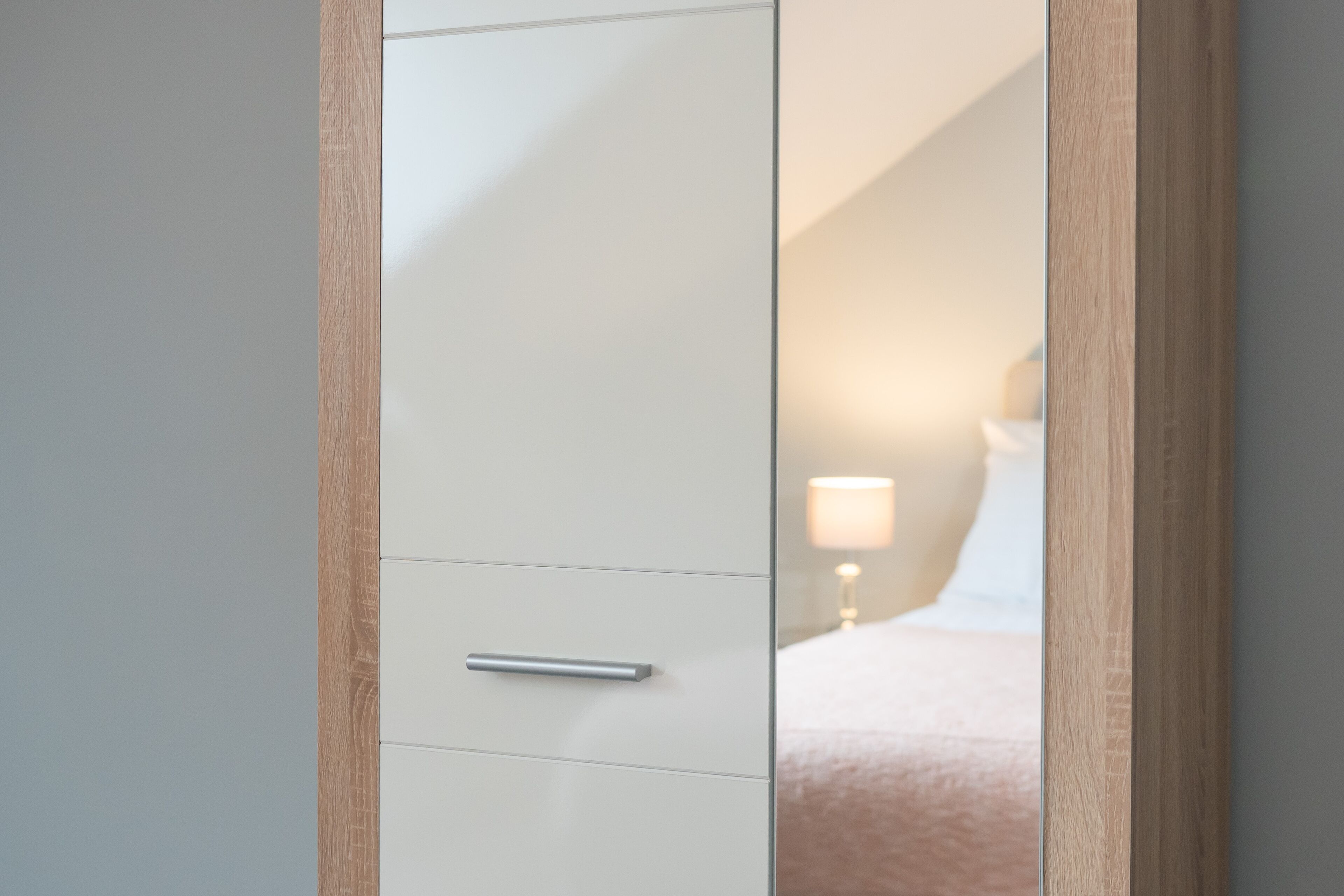 A white wardrobe with a wooden frame and a single drawer.