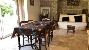 A dining area with a table set for six, a sofa, and a stone wall. - Gite Alcove in a farmhouse beach and coastal path on foot (Névez)