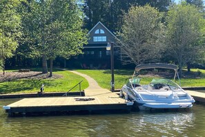 Een boot afgemeerd aan een houten steiger, met een huis op de achtergrond.