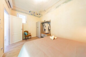 A bedroom with a bed, a chair, a wardrobe, and a small table.