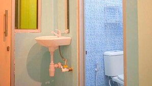 A bathroom with a sink, mirror, and toilet. - Roomz Budget (Semarang)