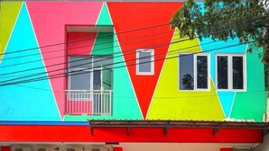 A colorful building with a red door and a mural of tropical animals. - Roomz Budget (Semarang)