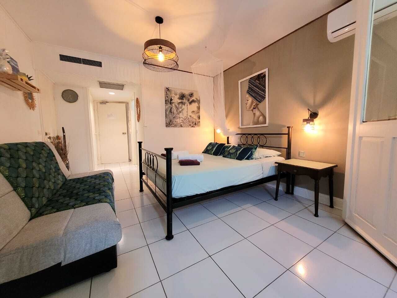 Une chambre à coucher comprenant un lit, un canapé, une table de chevet, une horloge murale et un tableau.