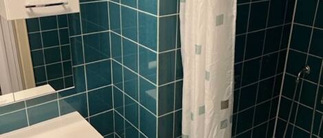 A bathroom with a white sink, a mirror, and a shower with a white curtain.