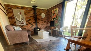 Ein gemütliches Wohnzimmer mit Backsteinwand, Kamin, einer Couch, einem Couchtisch und einem Essbereich mit Stühlen.